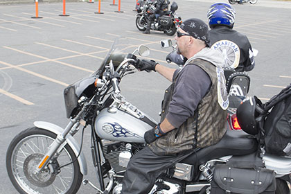 Riders wait on their motorcycles in the parking lot.