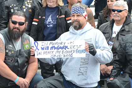 A man holds a sign while posing for a photograph with other riders.