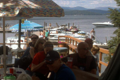 People sitting by a lake. Boats and a dock are in the background.