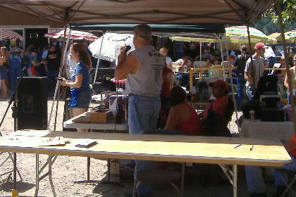 Crowd of people at event and under tents.