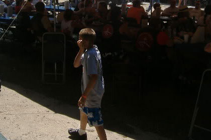 Boy walks in front of crowded eating tents.