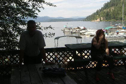 People sit on a deck overlooking a dock full of boats.