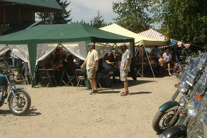 Motorcycles in foreground, with tents and people in the background.