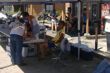 People sign up at a table underneath a tent.