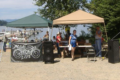 Booths and speakers set up next to a dock and a lake.