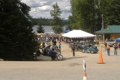 Far away shot of parking lot filled with motorcycles and tents.