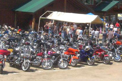 A lot of motorcycles and people in parking lot.