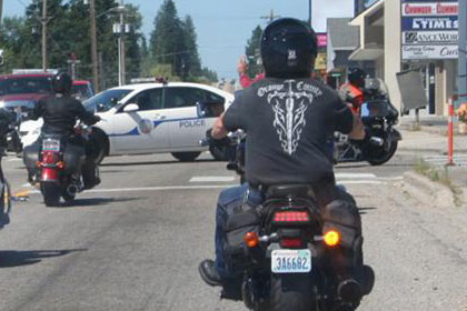 Two lines of motorcycles on road driving away from camera.