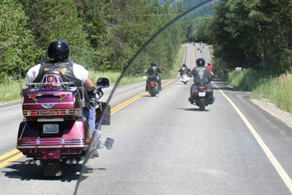 Motorcycles on road driving away from camera.