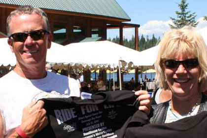 Two people pose with their Ride for Life 10th Anniversary T-shirts.