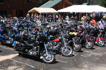 Lots of motorcycles fill parking lot outside of event venue.