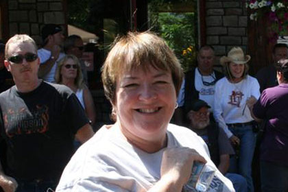 Woman smiles for camera. Lots of other people in the background.