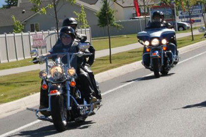 Two lines of motorcycles on road driving towards camera.