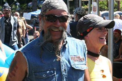 Man smiles for camera as he walks past with a woman.