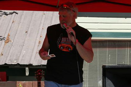 Man speaks through microphone under bright red tent.
