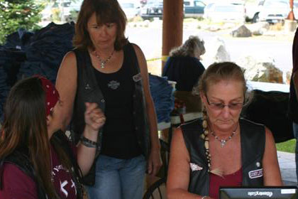 Several woman talk around tables full of Ride for Life t-shirts.