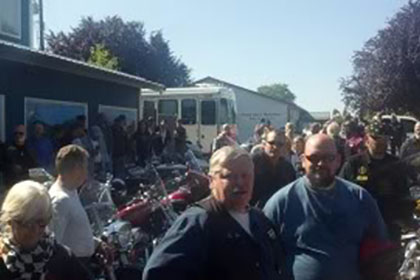 People gathered around motorcycles in the parking lot.