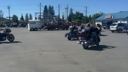 Some riders on their motorcycles in the parking lot.
