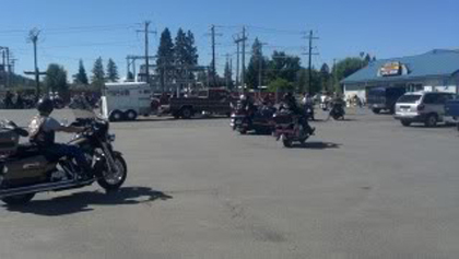 People on their motorcycles in the parking lot.
