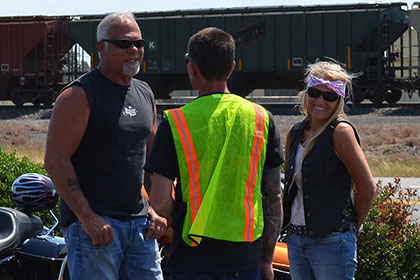 Standing next to their motorcycles.