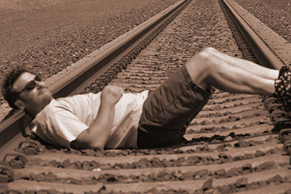 Man relaxing on railroad tracks.