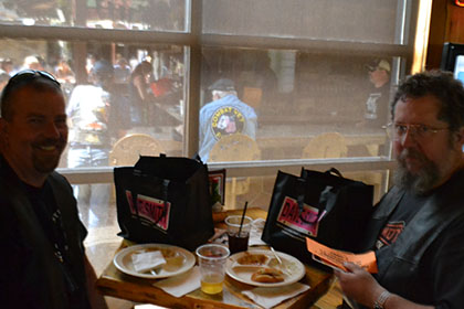 Couple of guys sitting at a table inside.