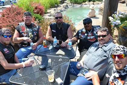 Group of guys sitting around a table outside.