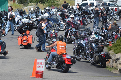 People on their motorcycles in the parking lot.