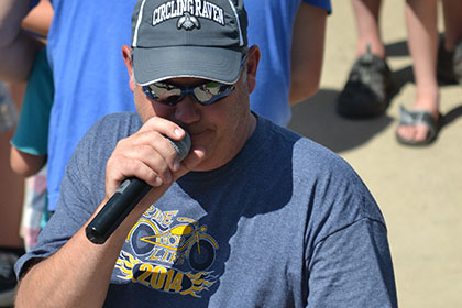 A man speaking on a microphone while pointing with his finger.