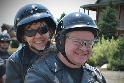 Two riders on a motorcycle smile for the camera.