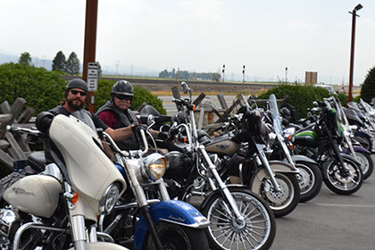 Couple guys sitting on their motorcycles in the parking lot.