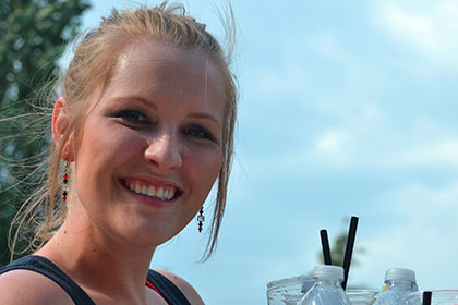 Smiling woman holds a tray of drinks.