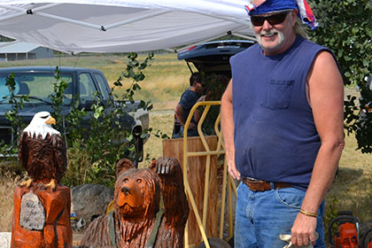 Men standing next to wood carvings.