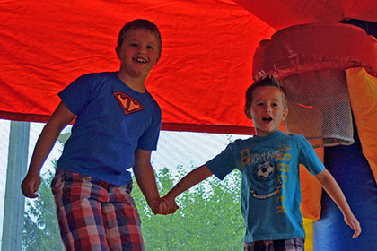 Two boys jumping in the bouncy castle.
