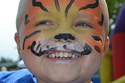 Child with their face painted like a tiger.