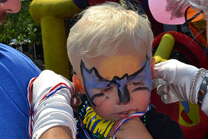Child with their face painted as Batman.
