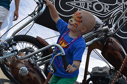 A painted face child on the display motorcycle.