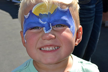 Young child with a painted face smiles for the camera.
