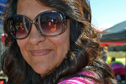 Woman wearing sunglasses has flowers painted on her arm.