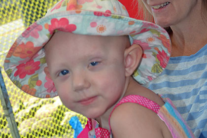 Child wearing a hat next to a woman at the event.