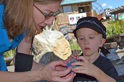 A woman gives a child a ball.