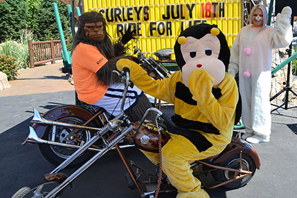 Skitch from Spokane Community College, a bee, and another person in costume, pose on motorcycles for a photograph.