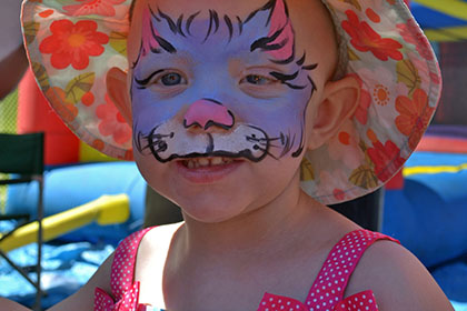 A child with a painted face and wearing a hat.