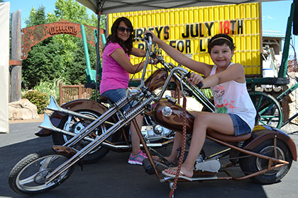 A woman and child pose on motorcycles for a photograph.