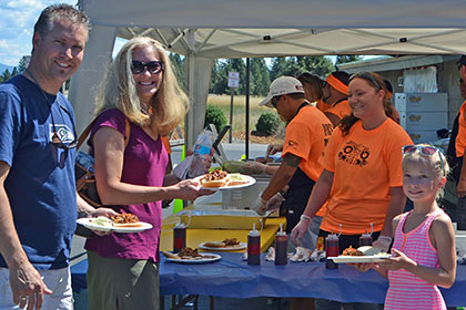 Adults and children holding their plates filled with food.