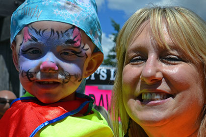 Woman holding a child with a painted face.