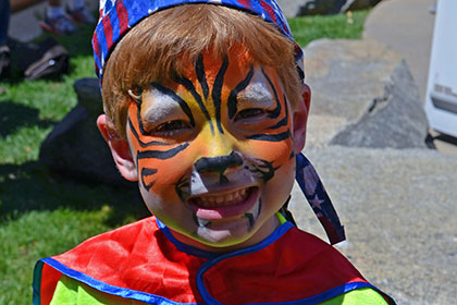 Child with their face painted like a tiger.