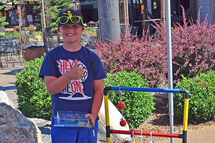 Child giving a thumbs up next to a game at the event.