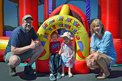 A man, woman, and two children pose for a photograph in front of a bouncy castle.