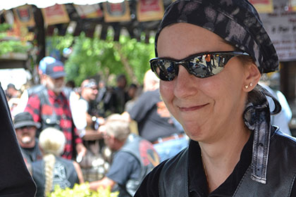 Woman with sunglasses eating barbecue at an outside table.